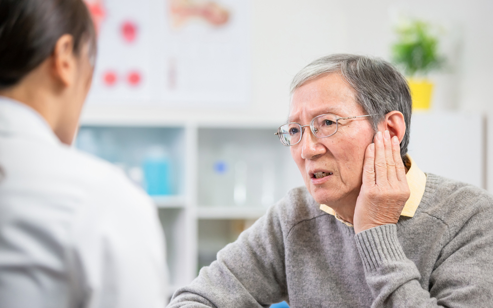 An older male patient discusses with his doctor suddenly losing hearing in one ear.