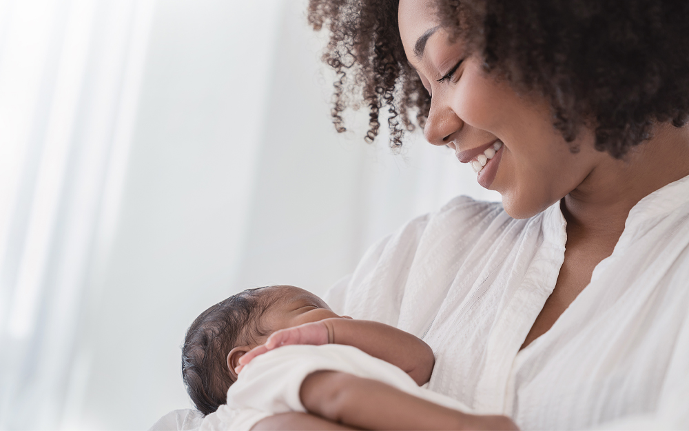 A mother holding a sleeping newborn baby in hospital