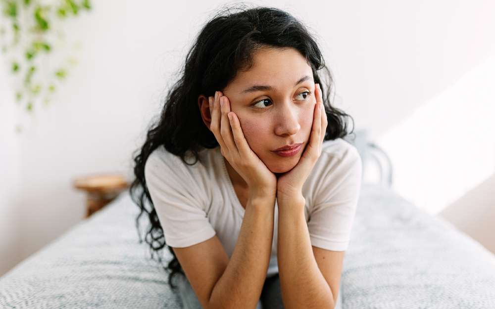 Young woman thinking on a bed