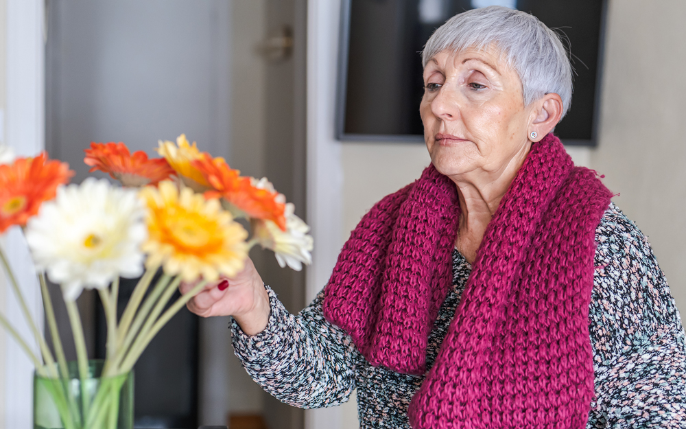 Elderly woman smelling flowers