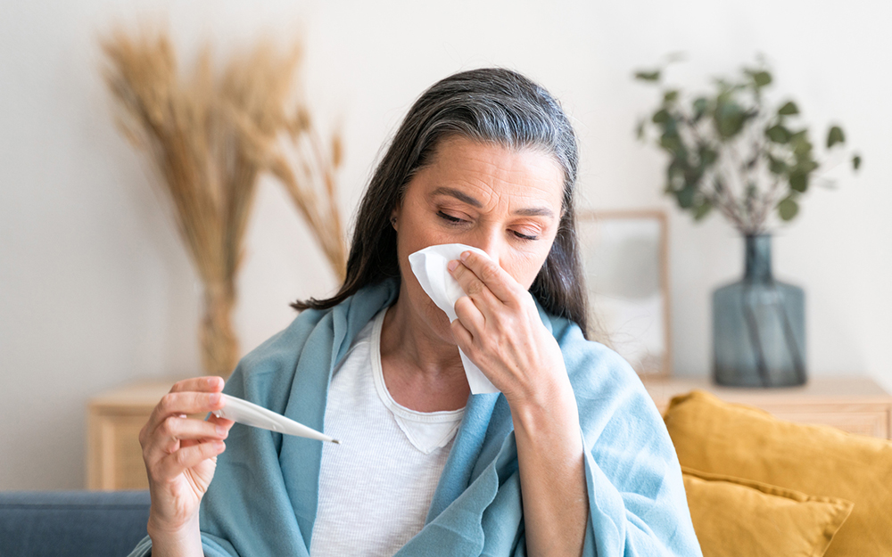 Woman with a tissue looking at a thermometer