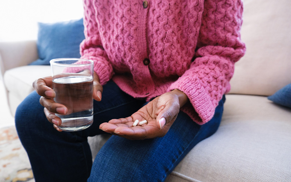 Woman holding capsules and a glass of water