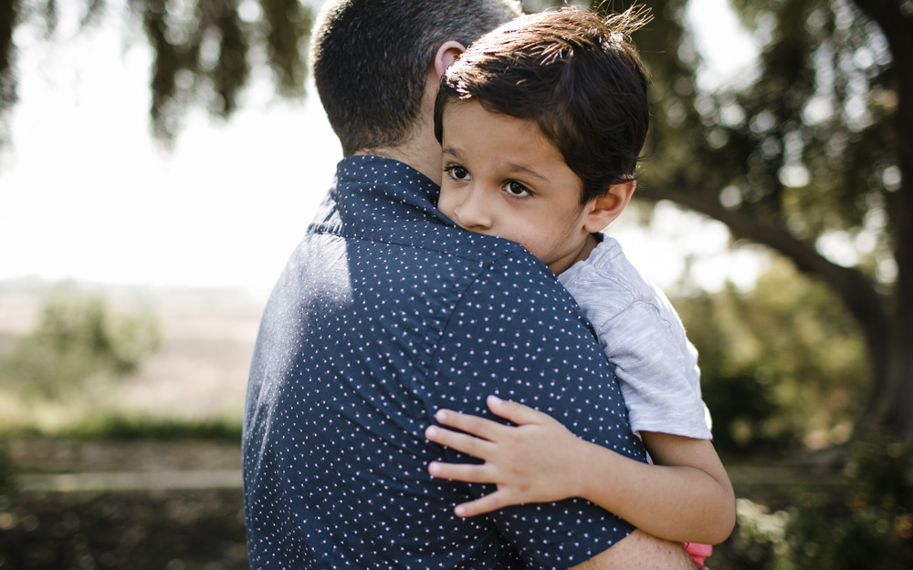 An autistic child being held by his father