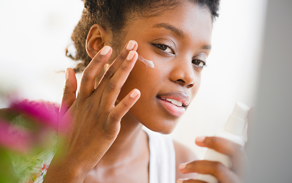 Woman putting sunscreen on face