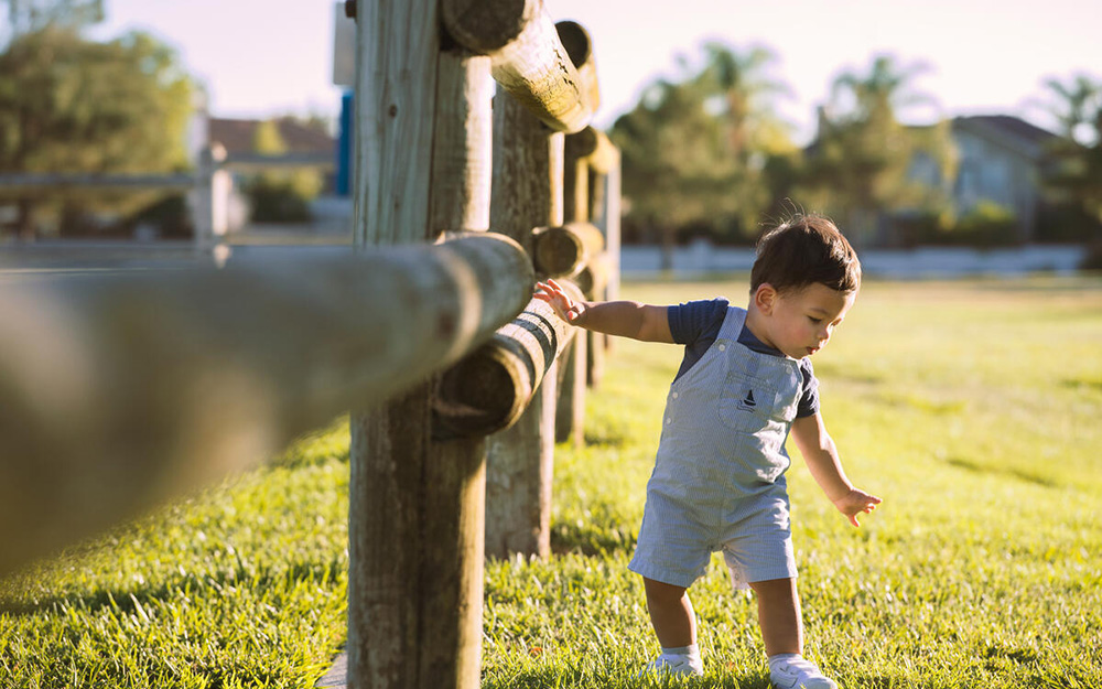 Baby boy walking outside.