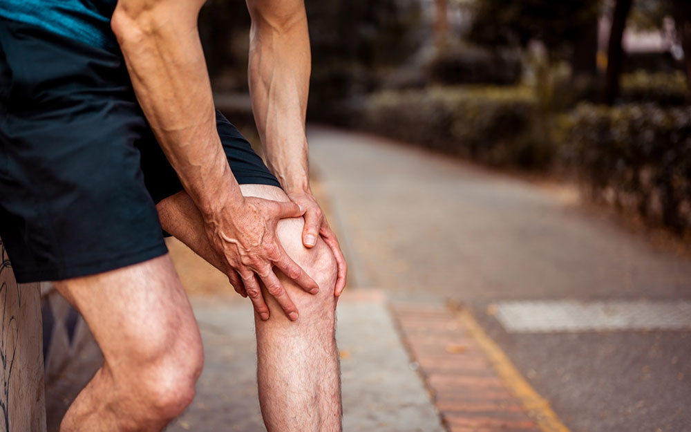 The athlete holds on to his knee as he feels pain.
