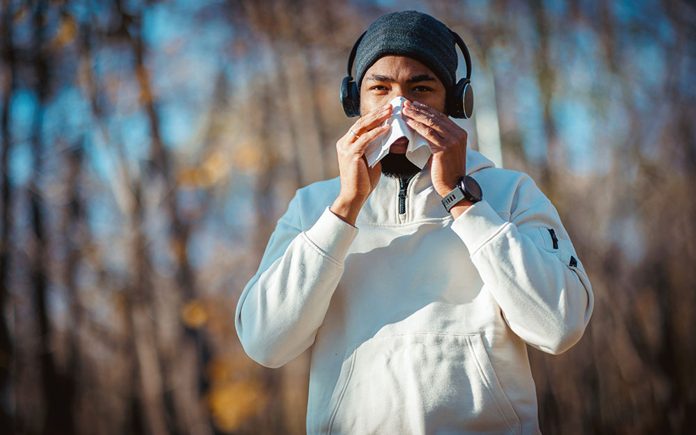 Man blowing his nose outside.