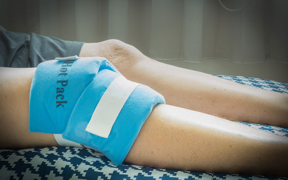 Person with a heating pad on their knee.