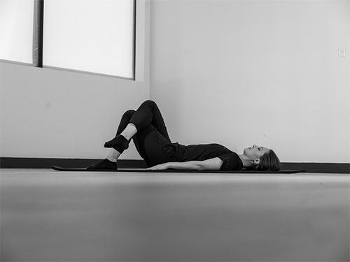 Woman lying on her back crossing her legs.