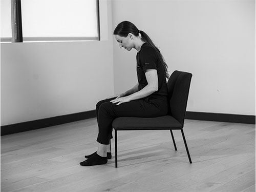 Woman sitting up on chair maintaining good posture raising her head.