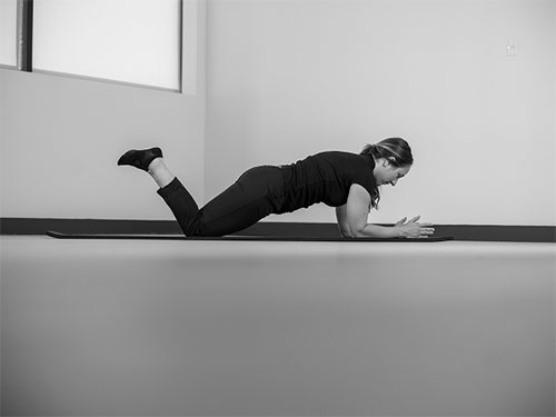 Woman with elbows and forearms on the ground, engage the core and lift up onto your knees or toes with a flat back.