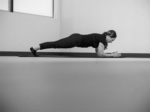 Woman with elbows and forearms on the ground, doing a plank.