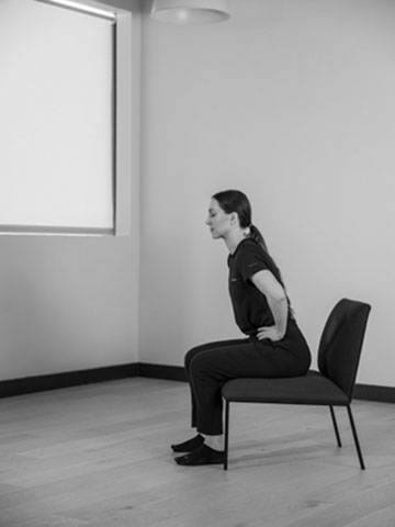 Woman sitting on chair leaning forward.