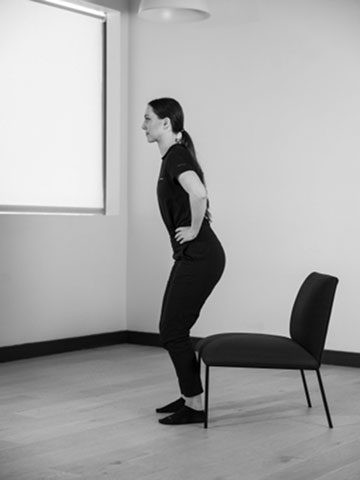 Woman standing up from getting up from chair.