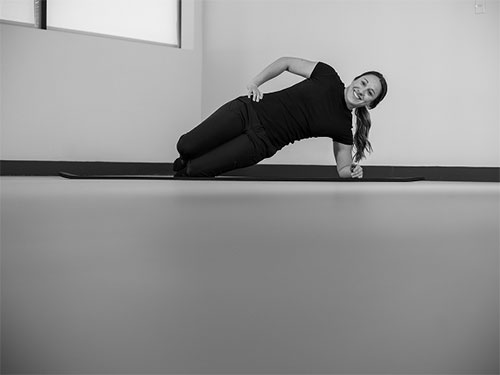 Woman performing a side plank on her knee.