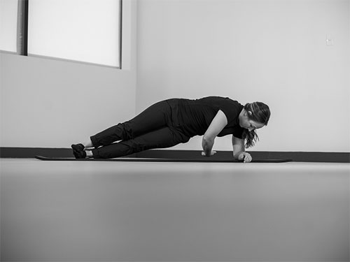 Woman performing a side plank, with one arm reaching underneath her body.