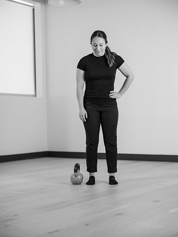 Woman standing with one arm on her side, looking down.