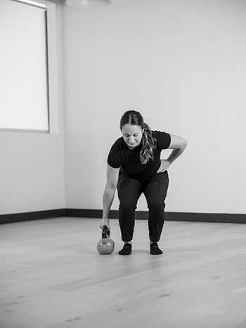 Woman holding a kettle bell in her hand.