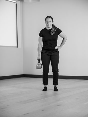Woman holding a kettle bell in her hand.