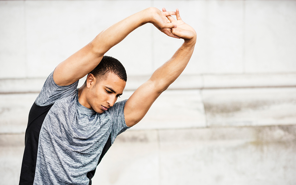 Athlete stretching his arms above his head.