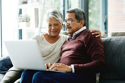 An elderly couple looking at a laptop