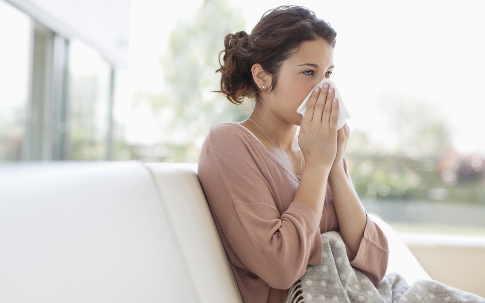 A sick woman blowing her nose