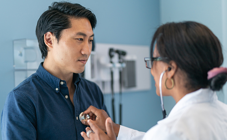 Woman doctor listening to man's heart.