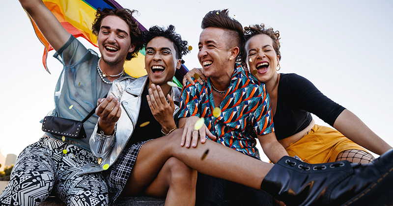 Four people holding a rainbow flag