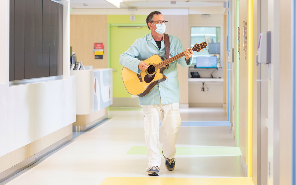 A Cedars-Sinai volunteer walking the halls with a guitar.
